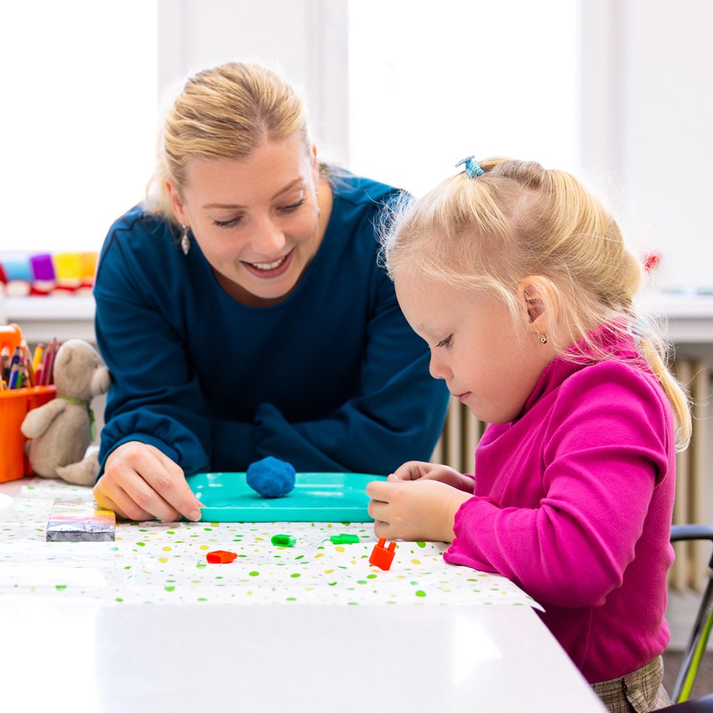 An occupational therapist works closely with a child.